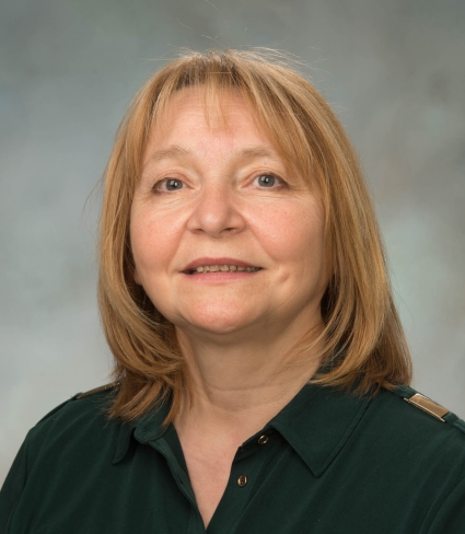 portrait of Lyubov Burlakova, a light-skinned person with shoulder-length blonde hair, dark grey eyes, wearing a green collared shirt