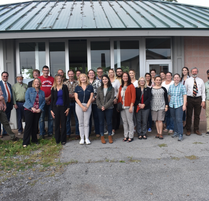 A group of about thirty people posing for a picture outside a small building.