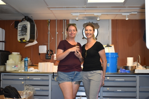 Two people pose for a picture in a lab on a large boat