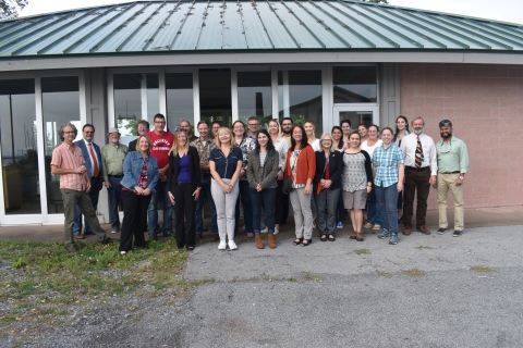 A group of about thirty people posing for a picture outside a small building.