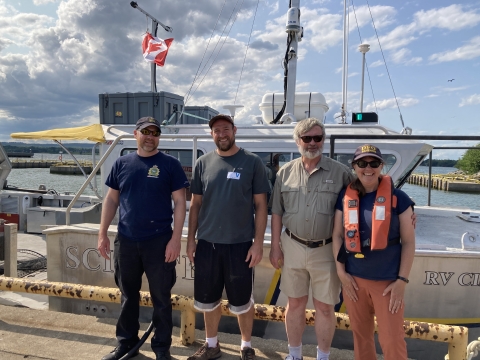 Four people pose beside a docked boat