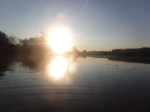 The sun rising over a wide creek.