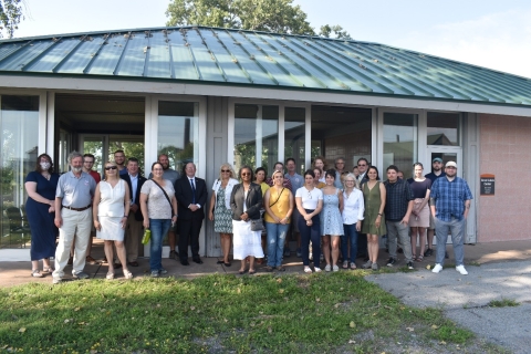 A group of about 30 people posing for a picture in front of a pavilion. Their attire is business casual.