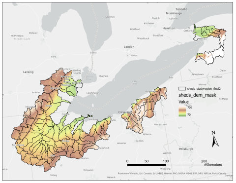 A map of the Lake Erie region with shapefiles belonging to class "sheds_studyregion_final2" on the land on the western margin in Michigan and Ohio, along the southern shore in Ohio near Cleveland, and in western New York on the eastern end of the lake. The shape files are colored with "sheds_dem_mask" which ranges from 70 to 706 (elevation). There is a scalebar showing up to 200 kilometers and a north arrow.