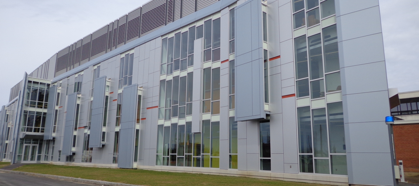 a three-story grey academic building with many windows