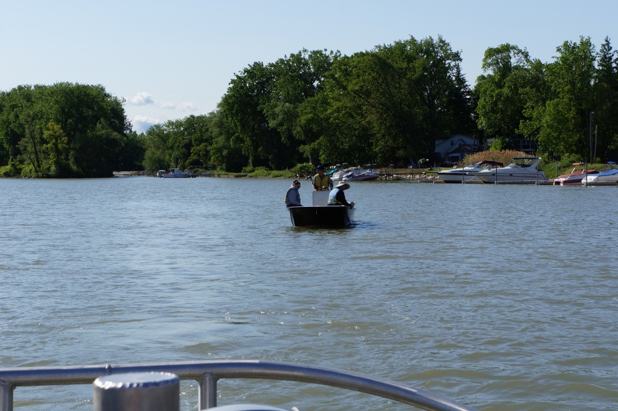 Three people sit on a boat on the water near some docks