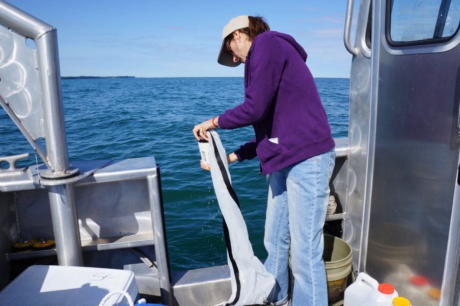 A person on a boat holds the jar at the bottom of a conical net.