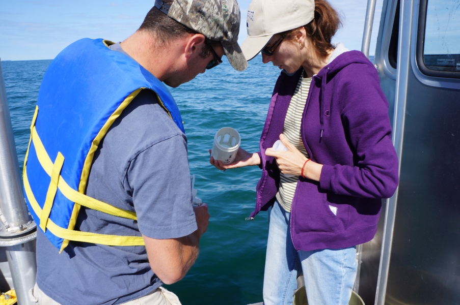 A person on a boat holds a jar while a second person looks at it