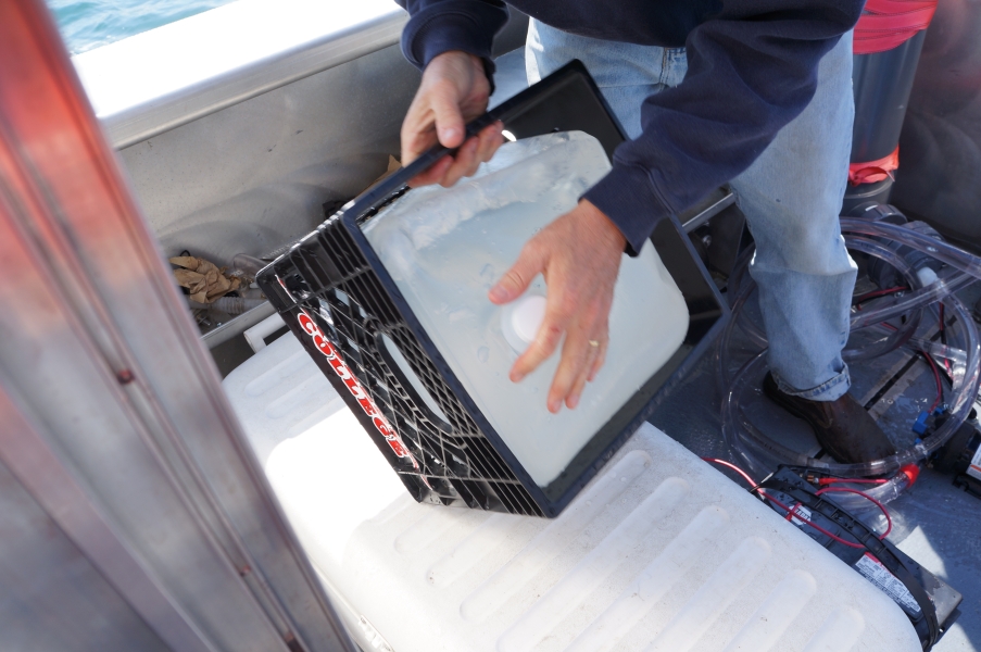 A person on a boat tips a closed cube container.