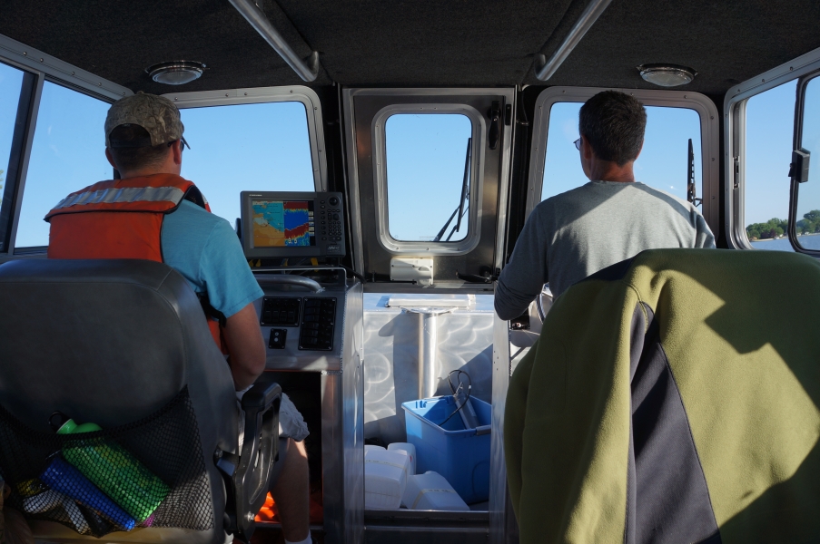 Two people sit inside the cabin of a boat