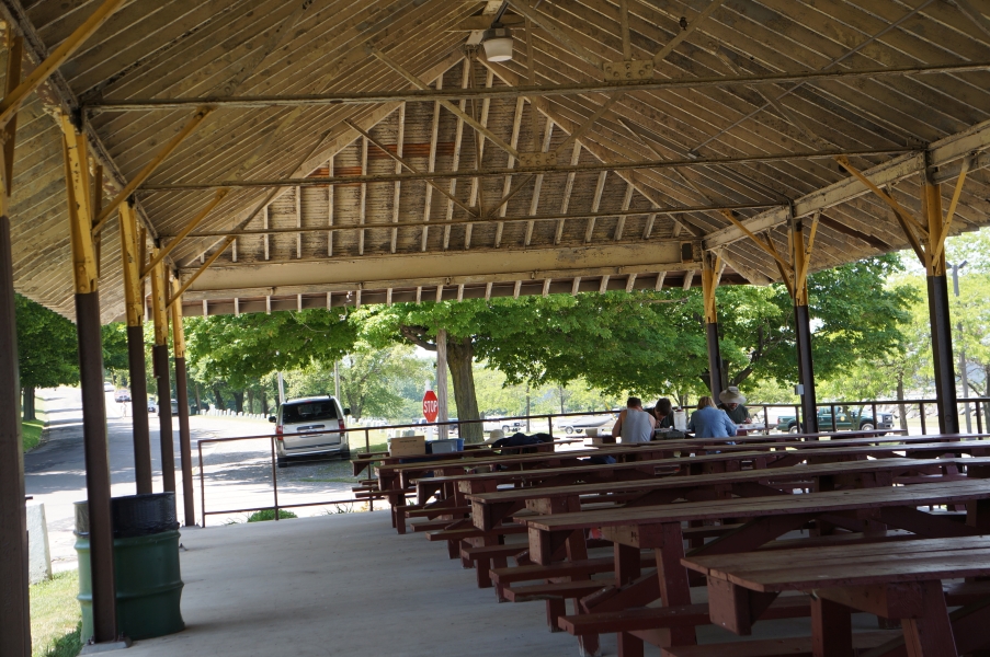 A group of people sitting at a table under a picnic structure