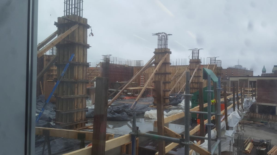 Wooden frames and steel rebar form walls and columns on the upper floor of a building under construction.