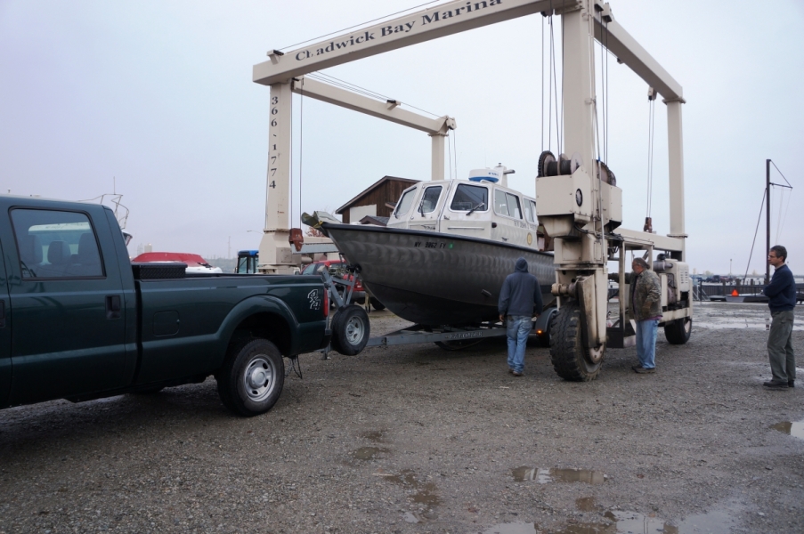 A large metal frame with wheels surrounds a boat on a trailer