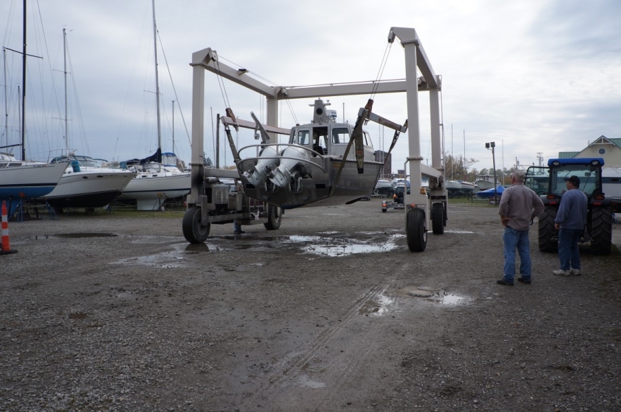 A large metal frame with straps holding up a boat. The engines of the boat are visible.