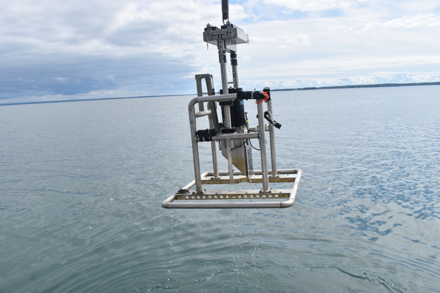 An instrument in a metal frame is suspended above a body of water.