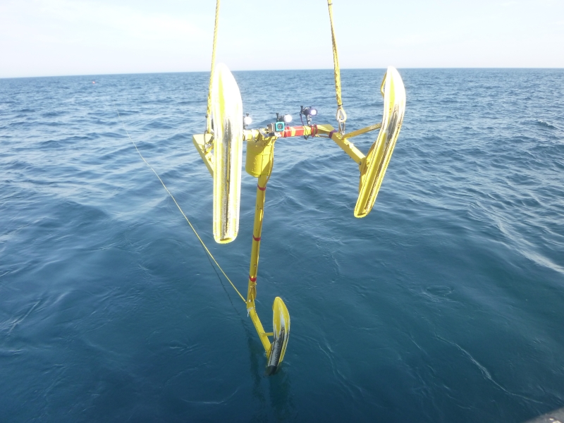 A metal frame with three sled feet is lowered into the water.