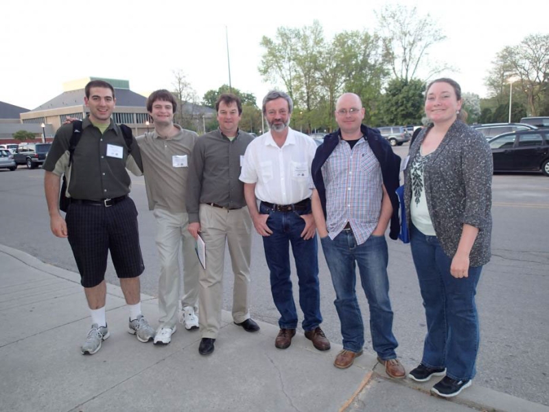 six people posing for a picture in a parking lot